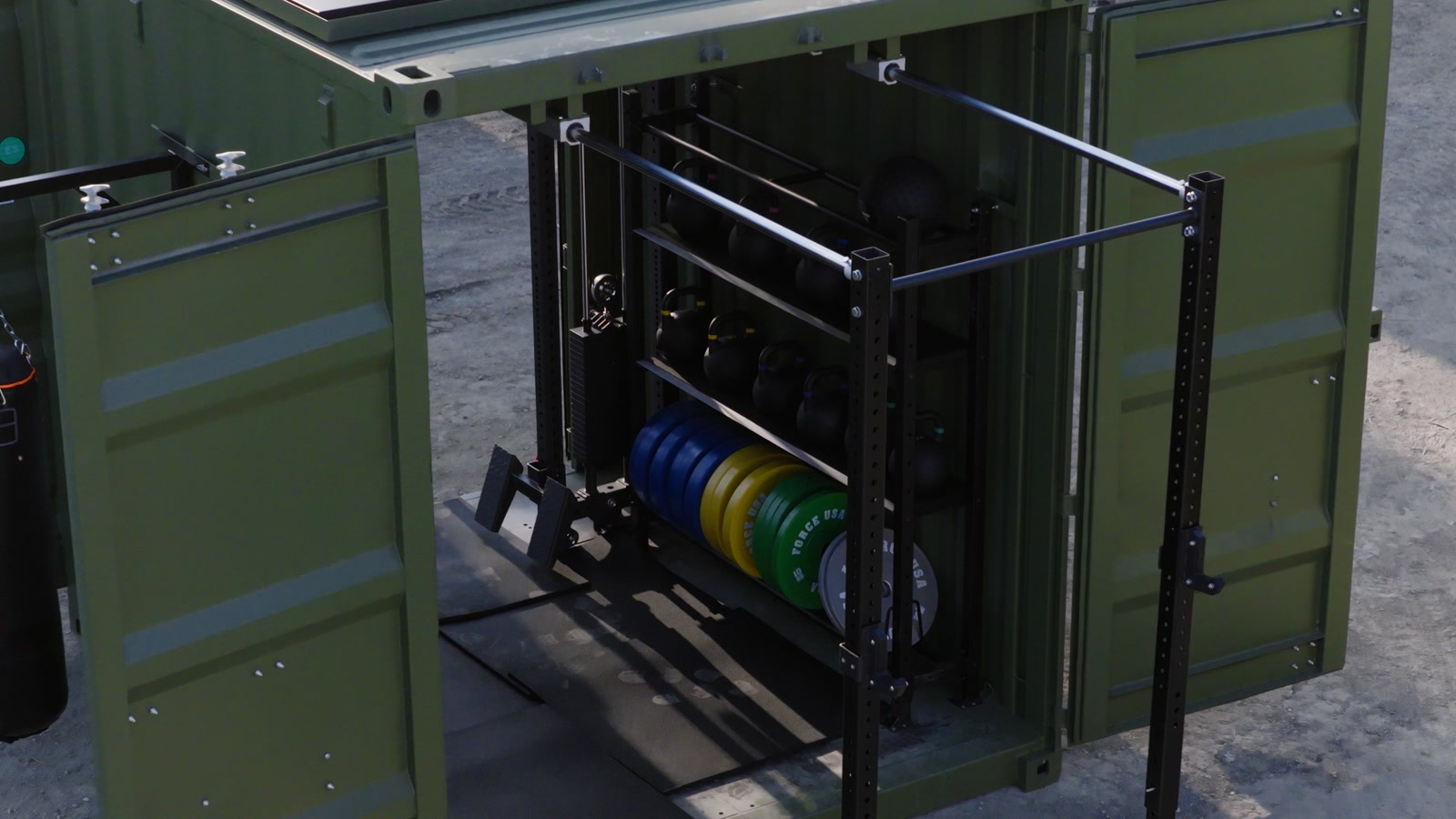 Open Rapid-10 showing the rig, stored kettlebells and coloured weight plates in the demonstration yard